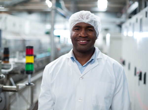 Portrait of smiling factory engineer standing in bottle factory
